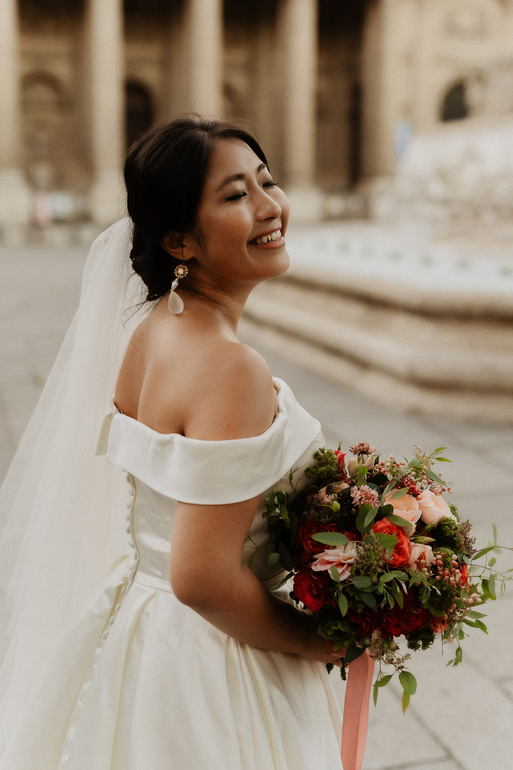 Haruka smiling with her bouquet of red and coral roses by the fountain of Saint-Sulpice