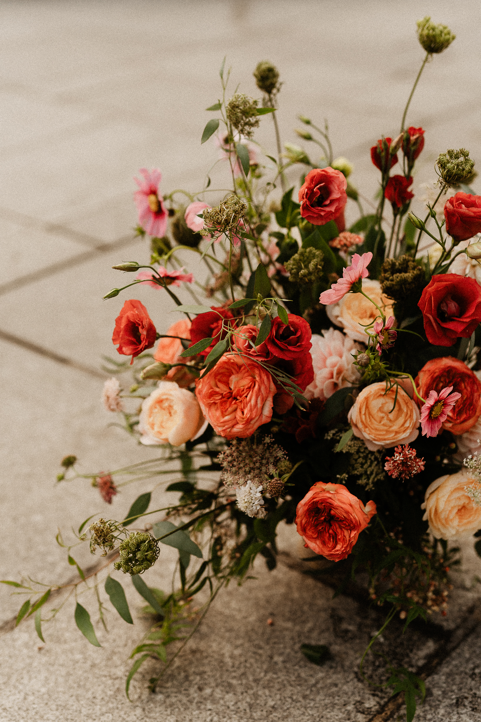 A tall arrangement of red, coral and pink roses on the stones of Place Saint-Sulpice