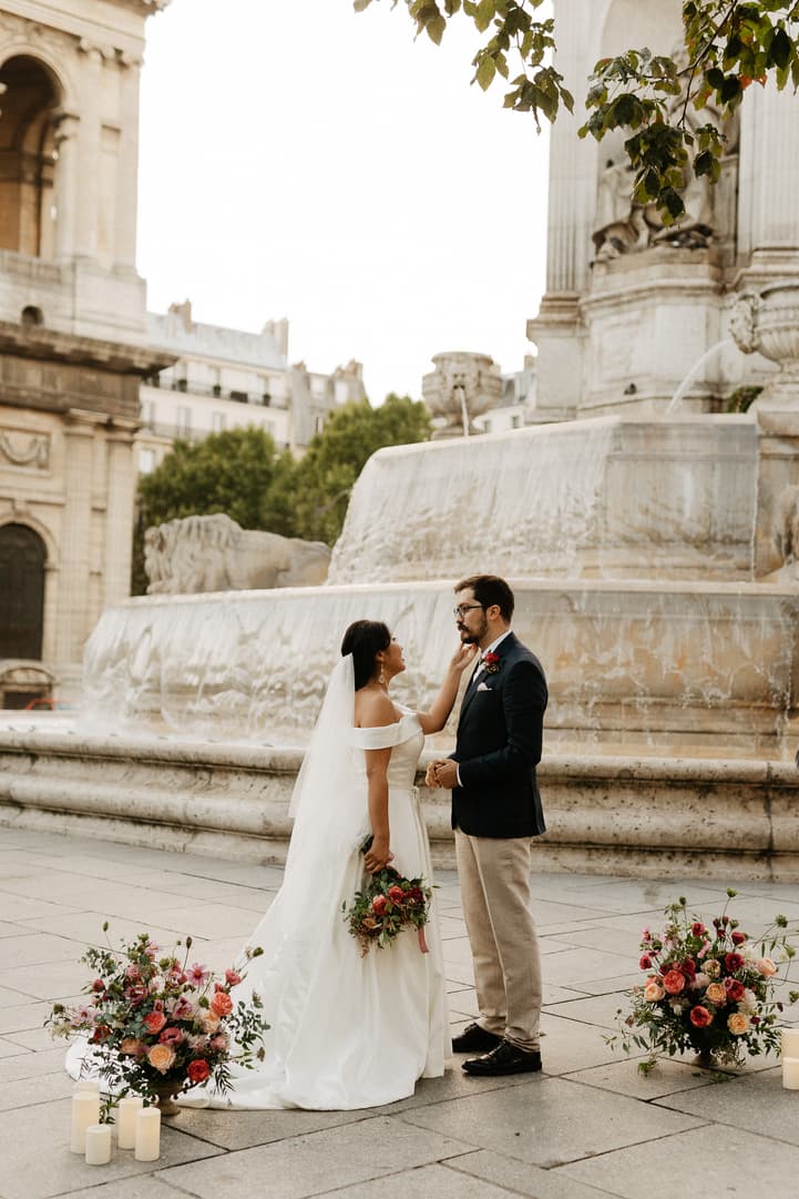 Haruka and Florent exchanging vows by the fountain of Saint-Sulpice, flowers and candles at their feet