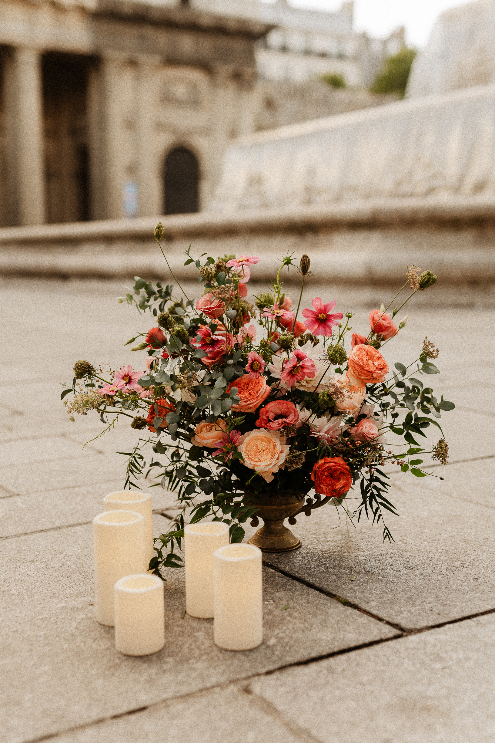 Coral and red flowers with white candles at the foot of the Saint-Sulpice fountain