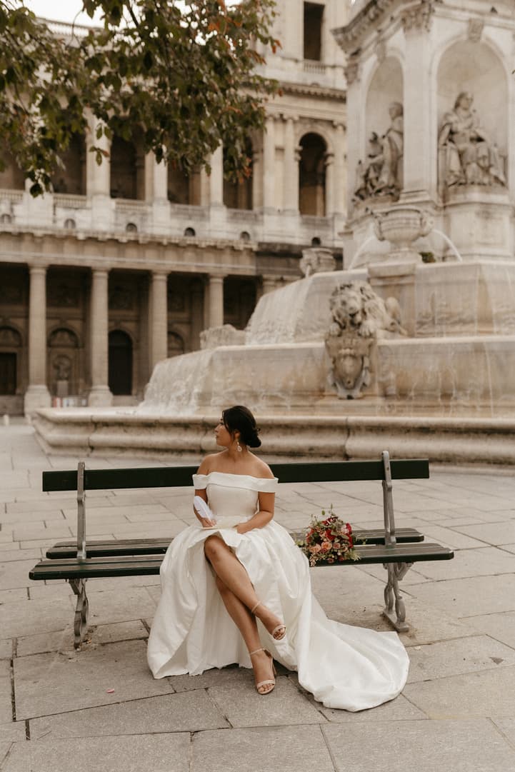 Haruka sitting on a green bench of Place Saint-Sulpice in her gown