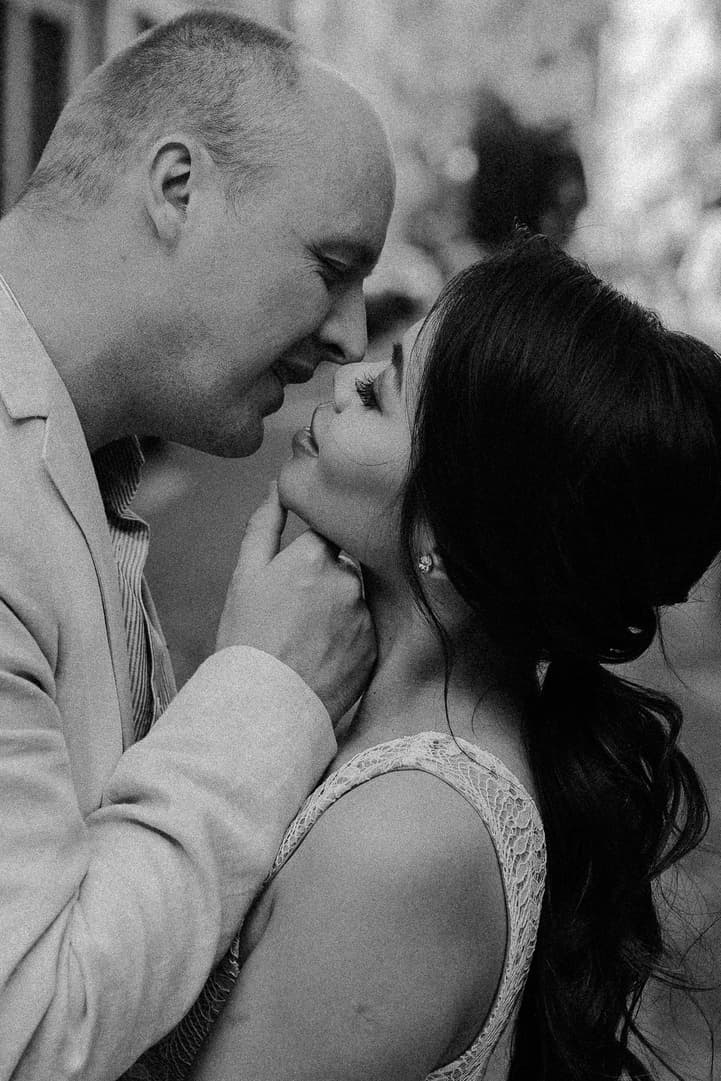 Black-and-white close-up of a couple on a Paris street, he cups her chin as they lean in together