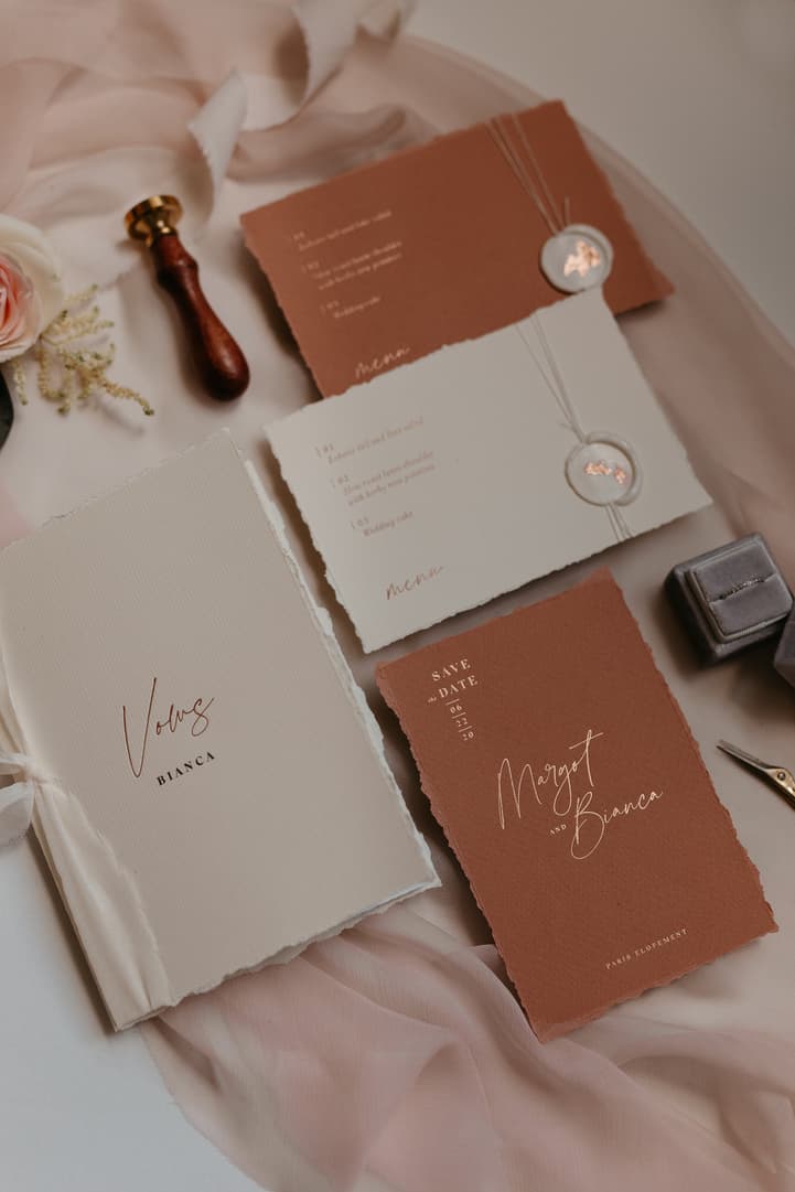 Flat lay of wedding invitation suites on blush fabric with wax seals and ribbons