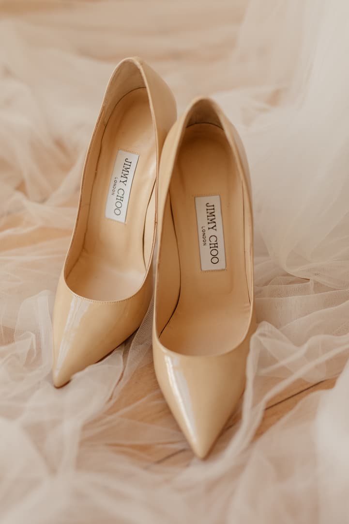 Ivory Jimmy Choo heels rest on soft tulle in warm window light, a bridal detail