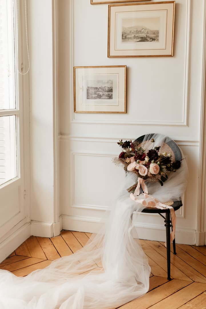 Bride's bouquet and veil drape over a chair in a sunlit Paris hotel room