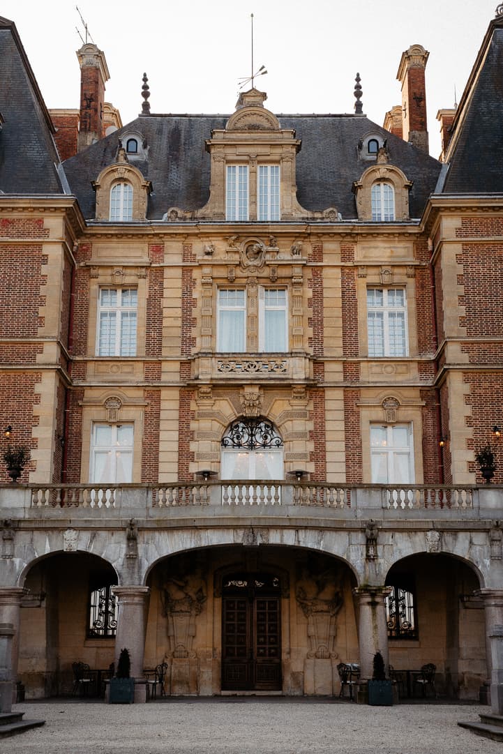 Soft light on a grand Paris hotel courtyard façade with arched arcade and wrought-iron details