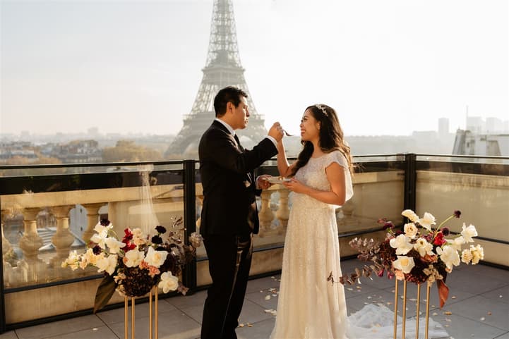 Bride and groom exchange rings on a terrace with the Eiffel Tower behind them at golden hour
