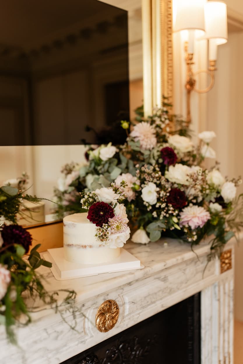 Floral wedding cake on a marble mantel in a softly lit Paris hotel room
