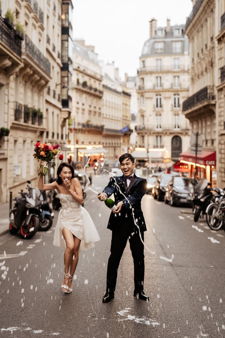 Fun asian couple champagne shower to celebrates their elopement wedding on the Paris street