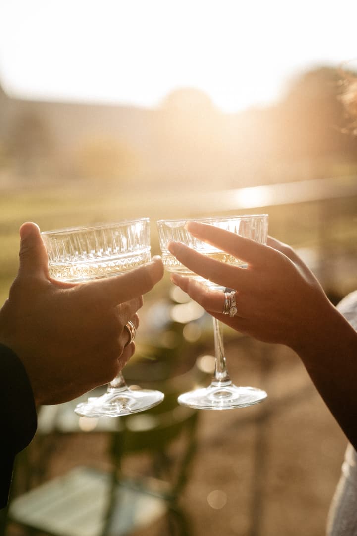 Bride and groom clink crystal glasses on a Paris terrace in warm golden light