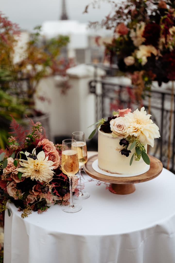 Wedding cake, florals, and champagne glasses on a Paris terrace in soft daylight