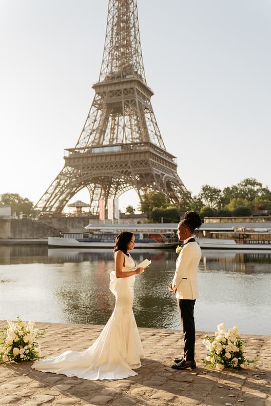 Bride and groom exchange vows by the Seine with the Eiffel Tower glowing in warm evening light