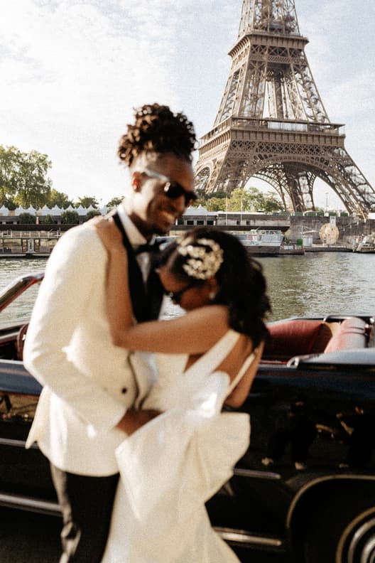Bride and groom embrace on a riverboat by the Eiffel Tower in soft afternoon light