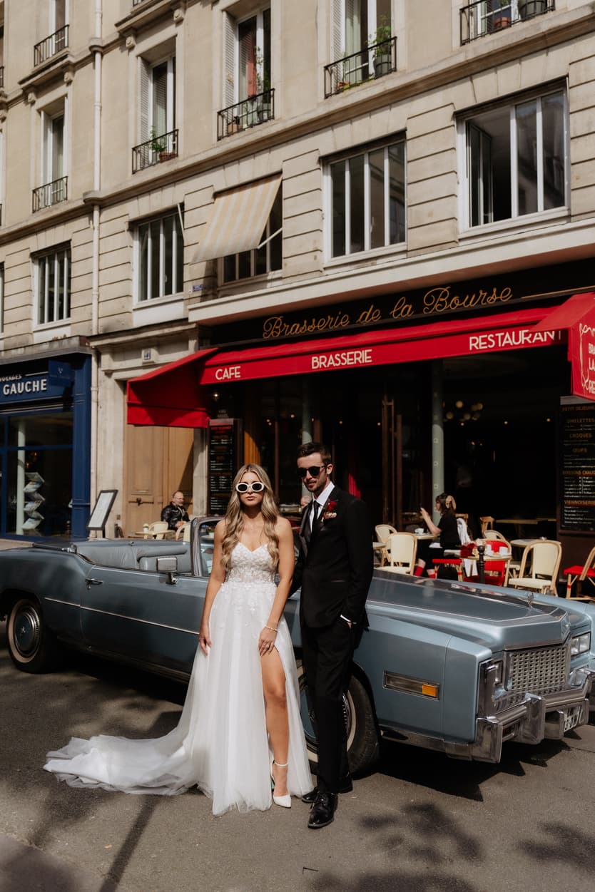 A bride and groom by a vintage convertible outside the Brasserie de la Bourse in Paris