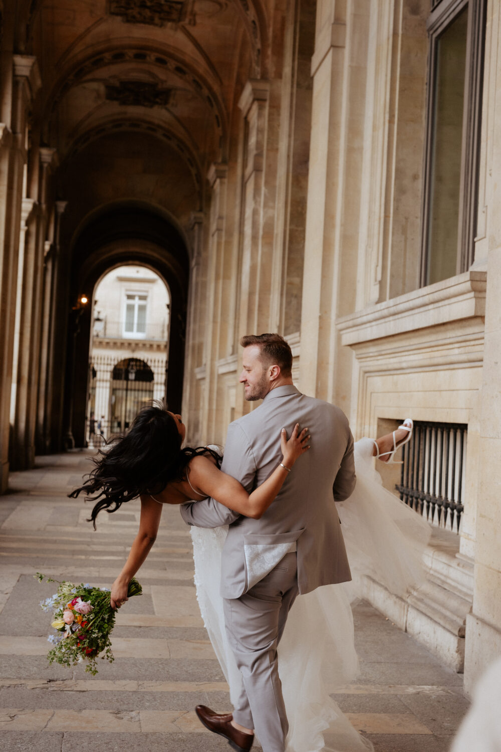 Groom hold bride up, the bride holding a bouquet of flower
Paris elopement Louvre
