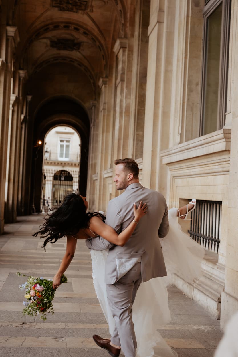 Groom hold bride up, the bride holding a bouquet of flower Paris elopement Louvre
