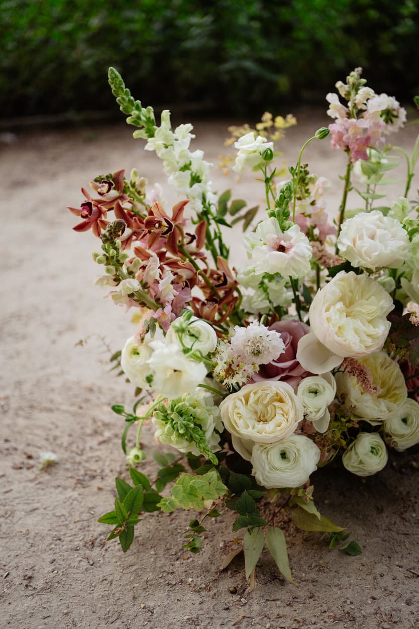 A low arrangement of white, peach and pink flowers on the gravel of a Paris garden