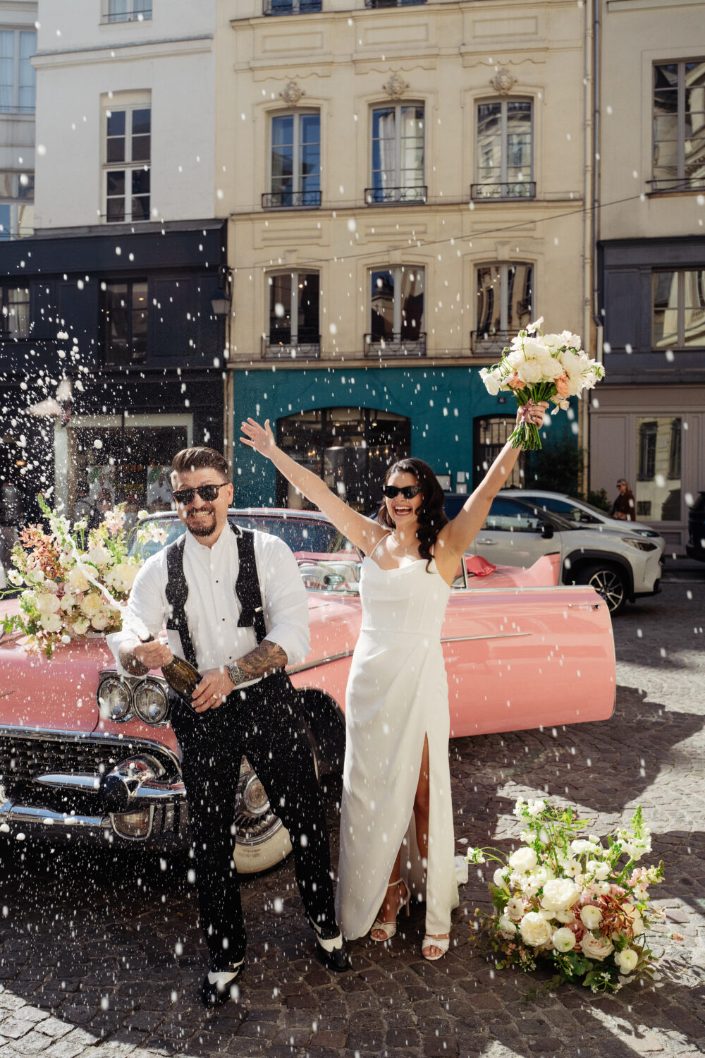 couple celebrating with champagne shower their elopement wedding with vintage car in Paris