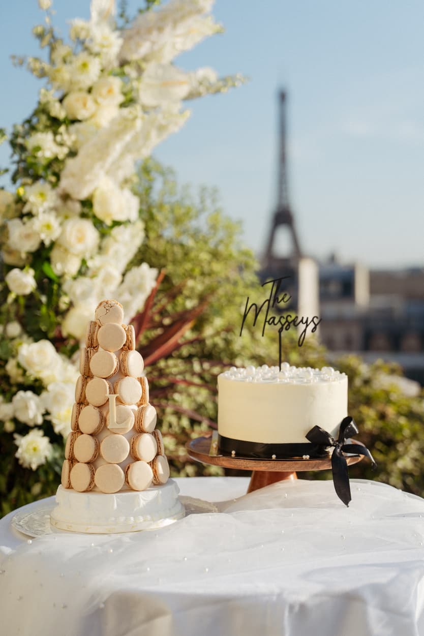 Wedding cakes on a white table with the Eiffel Tower blurred behind them on a Paris terrace