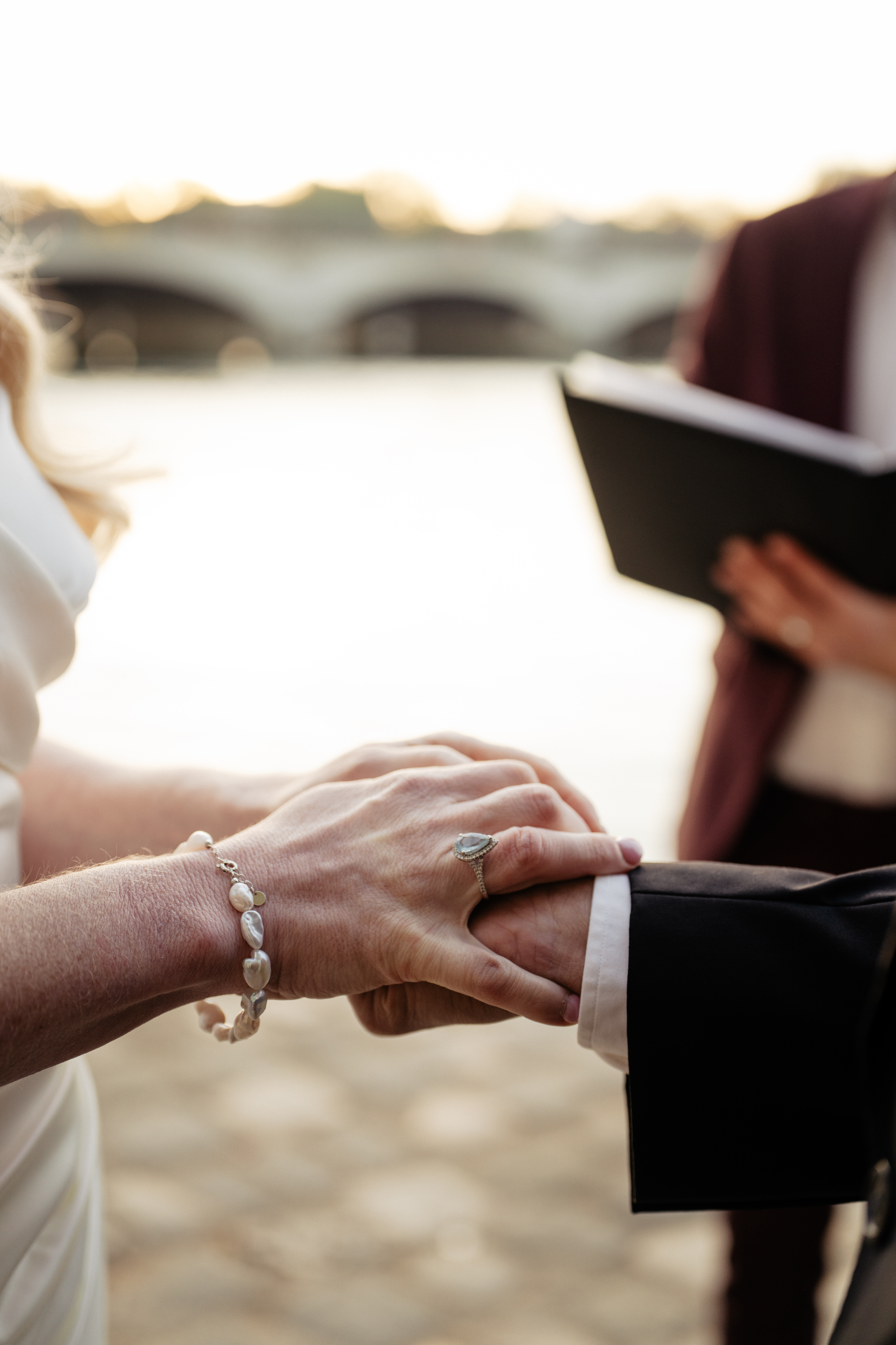 Collie and Gus holding hands as the rings are exchanged