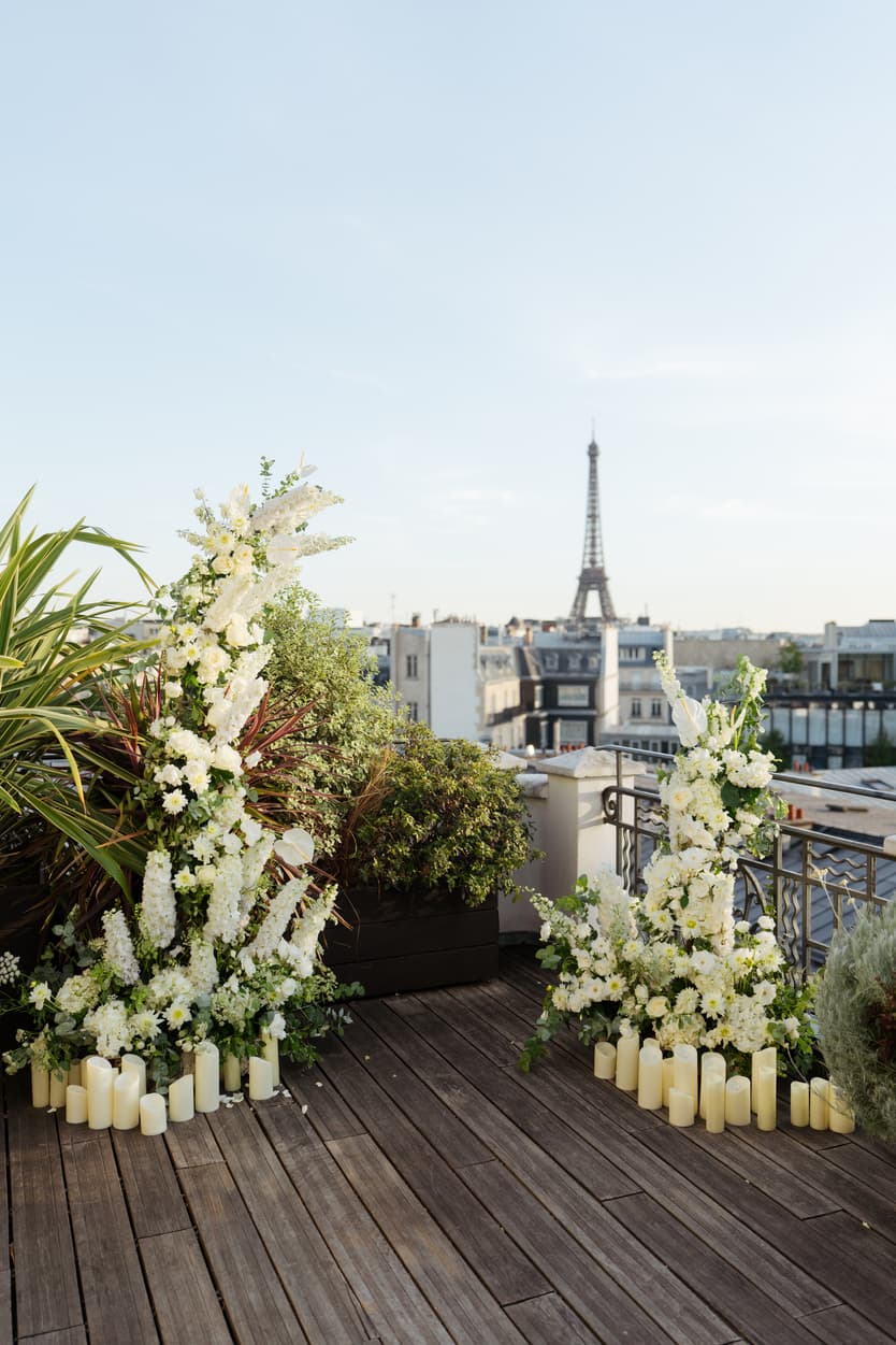 Floral wedding arches and candles frame the Eiffel Tower from a Paris rooftop terrace
