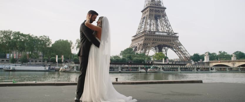 A couple embracing by the Seine, the Eiffel Tower behind them