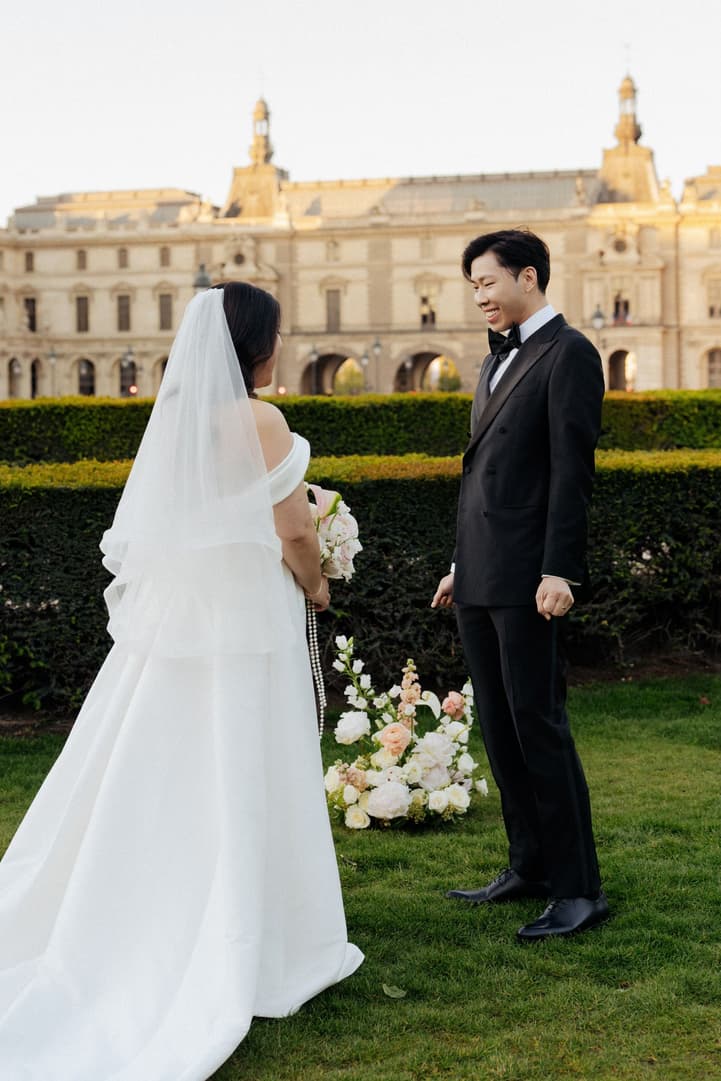 Jason smiling at Nancy in her wedding dress and veil during their first look in Paris