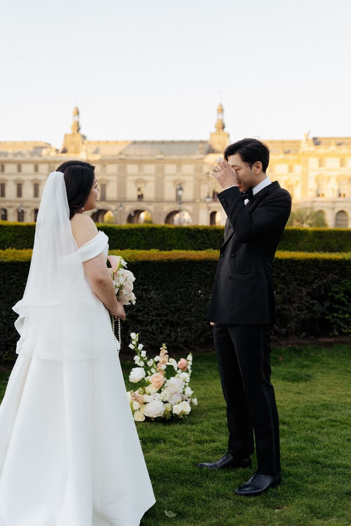 Jason wiping a tear as he sees Nancy in her wedding dress in front of the Louvre