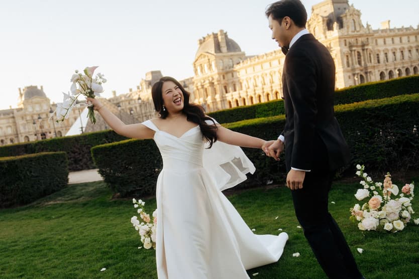 Nancy and Jason dancing hand in hand on the lawn in front of the Louvre