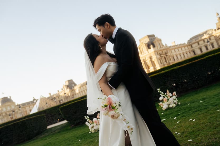 Jason kissing Nancy in the garden of the Louvre after their vows