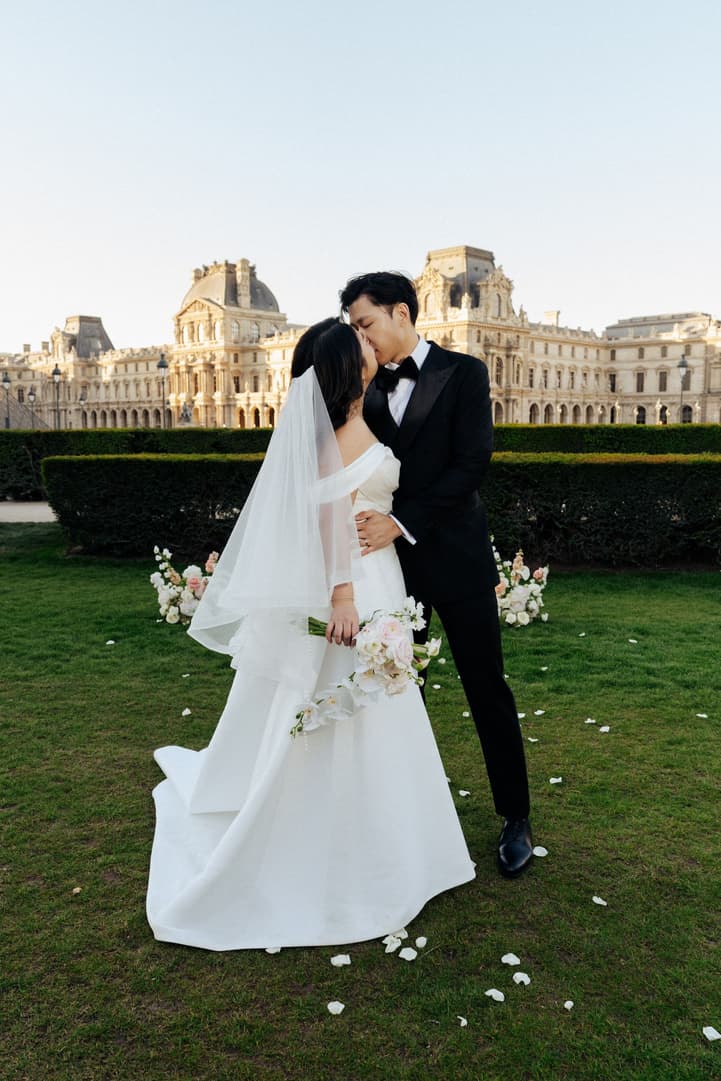 Nancy and Jason kissing on the lawn in front of the Louvre after their elopement ceremony