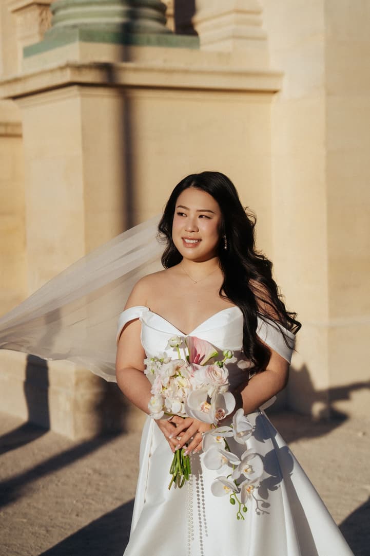 Bridal portrait of Nancy with her veil and bouquet in the sunrise light at the Louvre