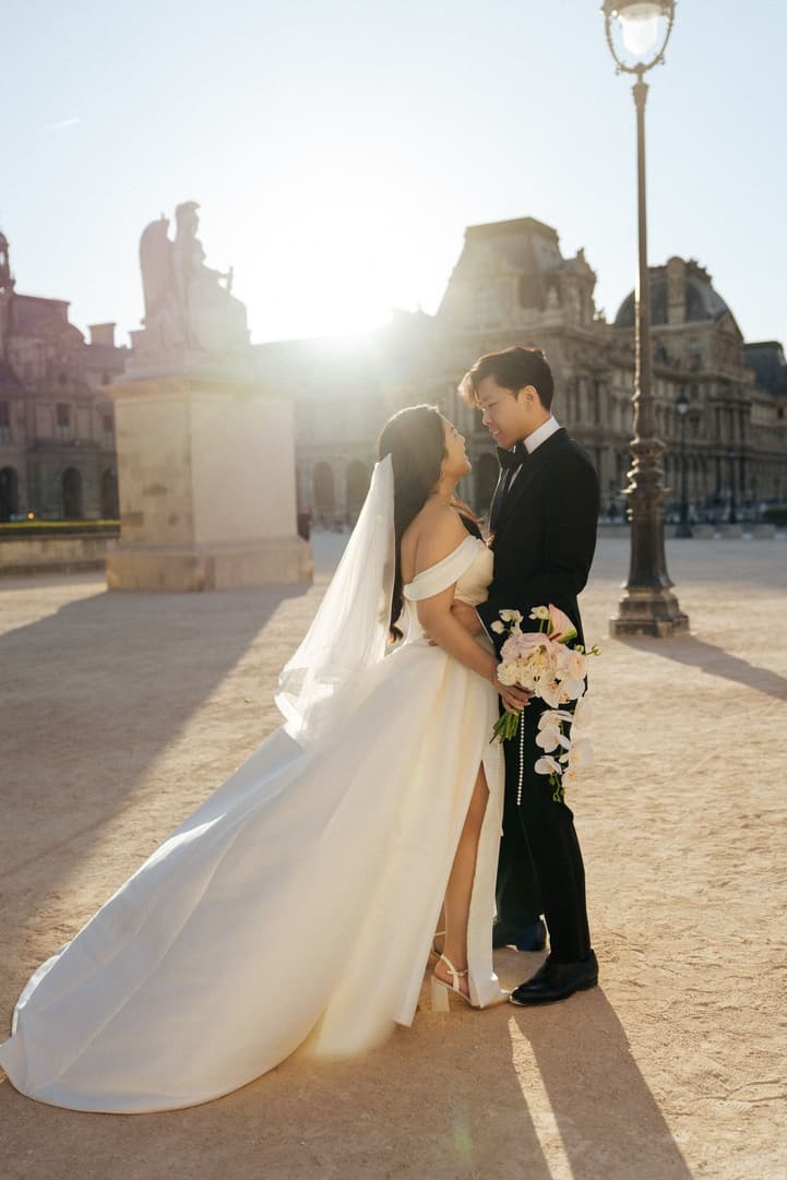 Nancy and Jason backlit by the morning sun beside a Paris street lamp at the Louvre