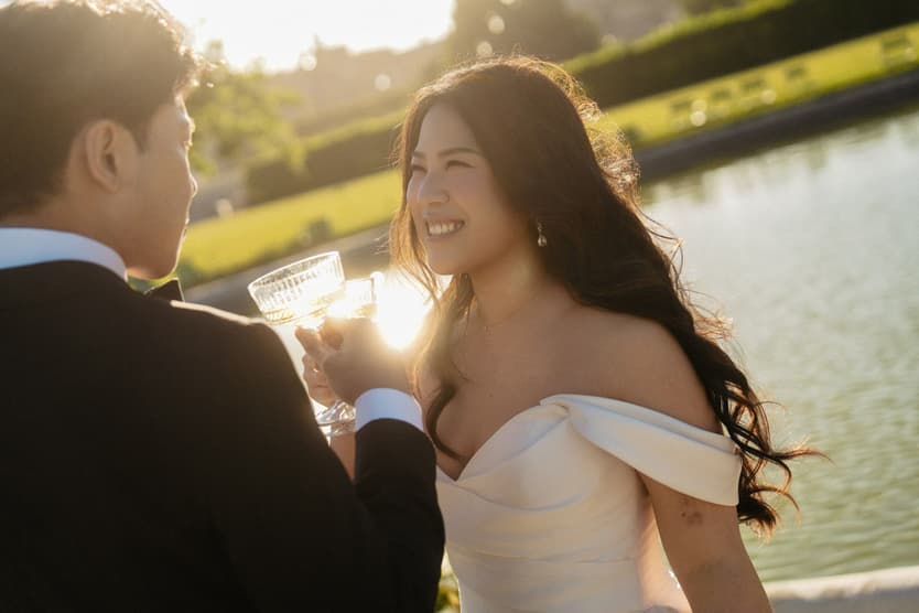 Nancy and Jason toasting with champagne coupes by the water in the Tuileries