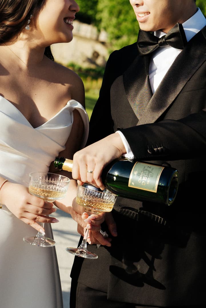 Jason pouring champagne into coupes for their wedding toast