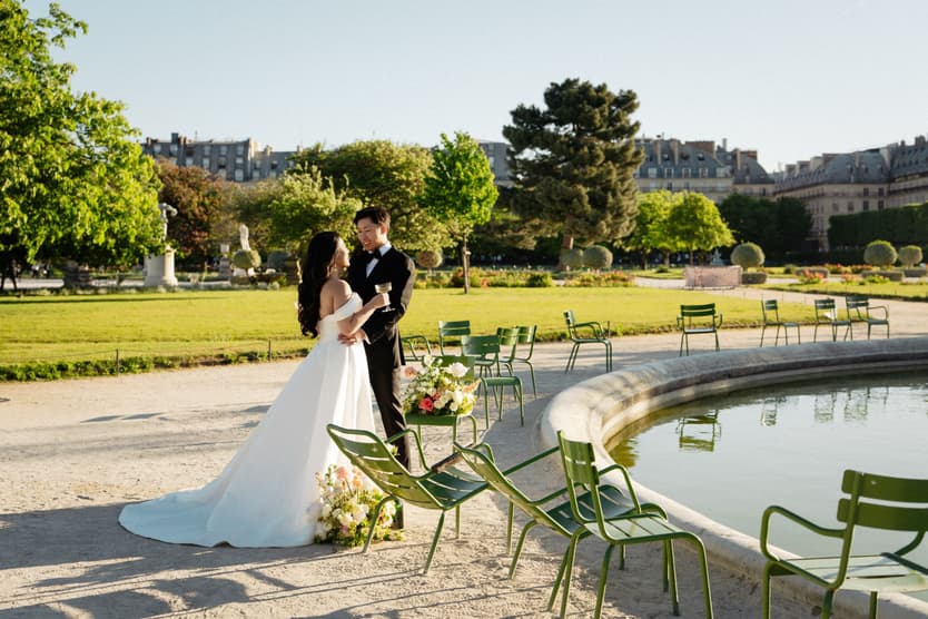 Nancy and Jason kissing by the Tuileries basin among the green garden chairs