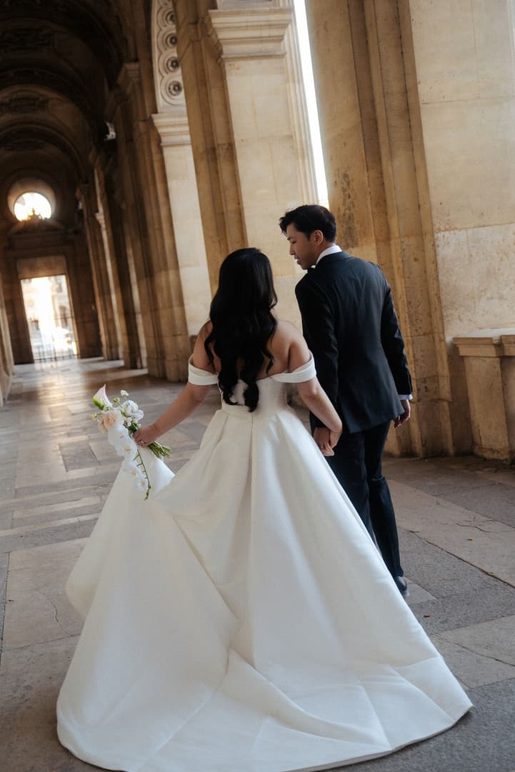Nancy's wedding dress and veil as they walk through the hallway of the Louvre