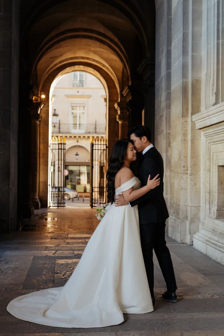 Nancy and Jason embracing in an archway of the Louvre