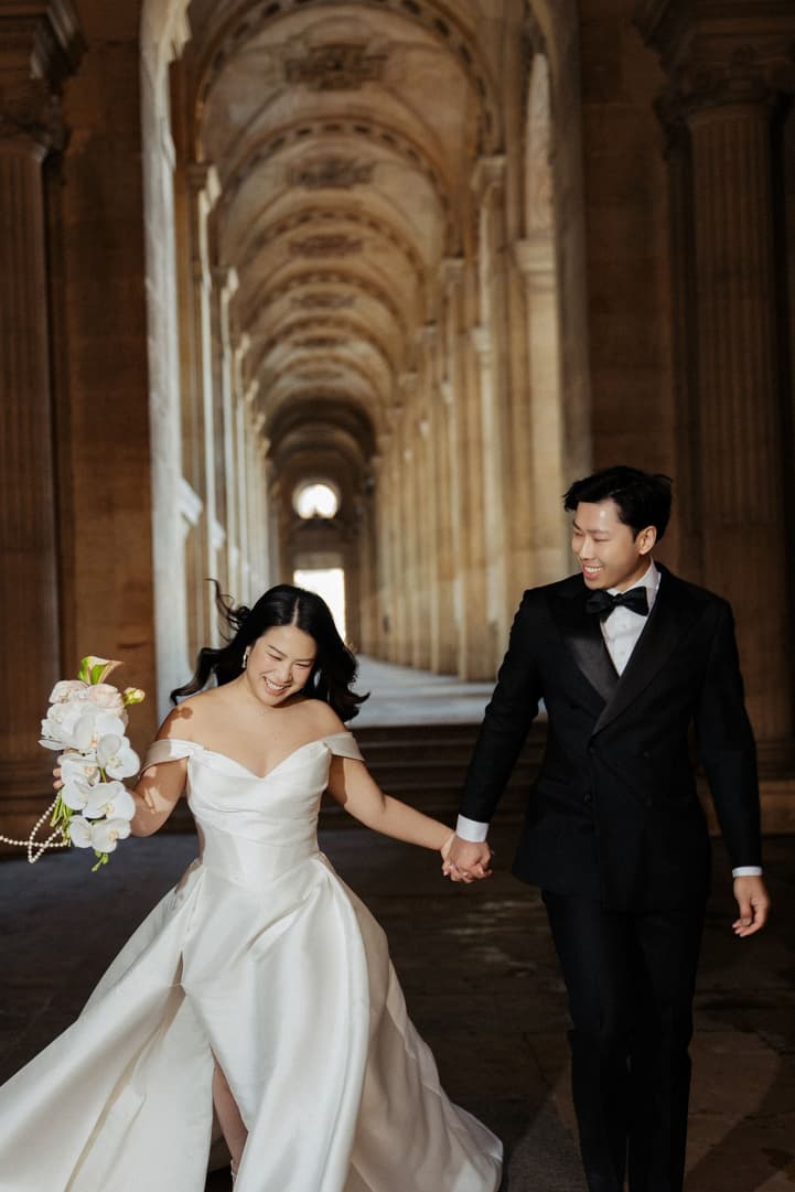 Nancy and Jason laughing as they walk through the colonnade of the Louvre