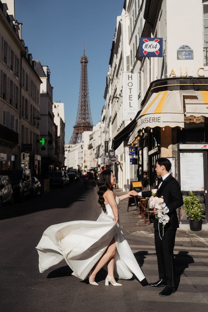 Nancy swirling her wedding dress in a Paris street with the Eiffel Tower at its end
