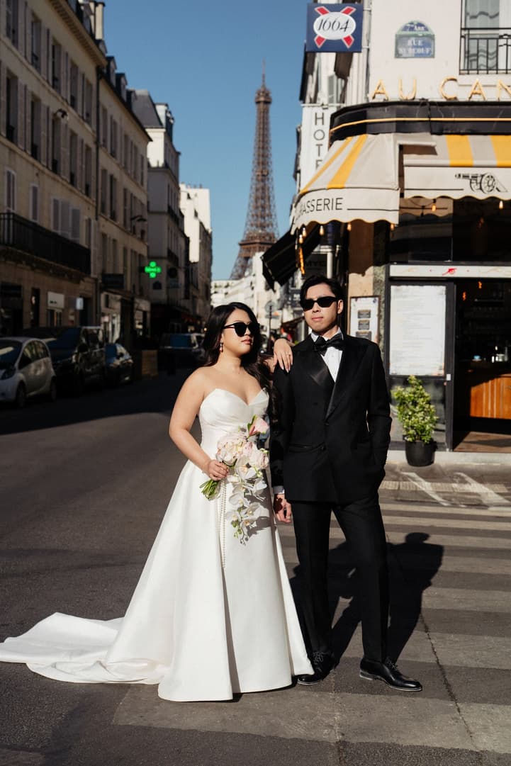 Nancy and Jason posing in sunglasses outside a Paris brasserie with an Eiffel Tower view