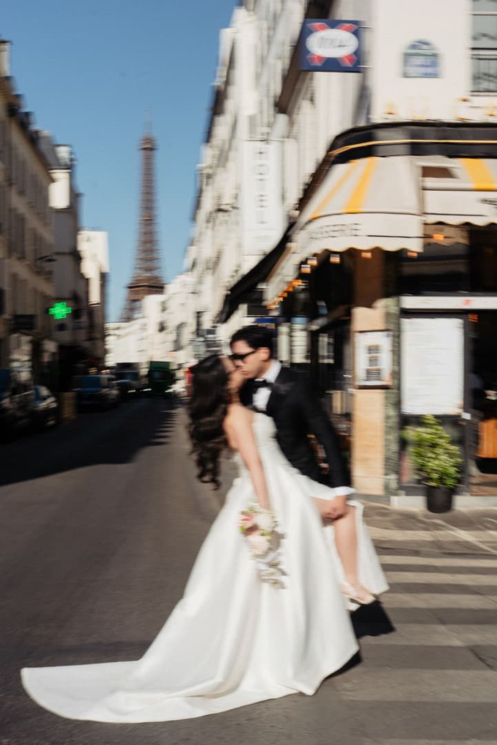 Jason kissing Nancy in the middle of a Paris street with the Eiffel Tower in the distance