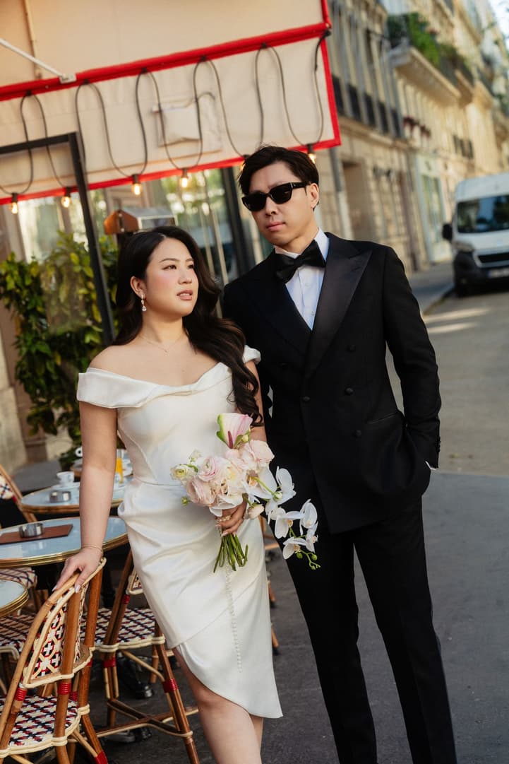 Nancy in her white mini dress beside Jason at a Paris café terrace
