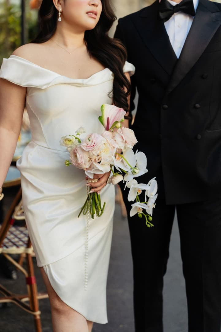 Nancy's second outfit, a white mini dress, with her orchid bouquet