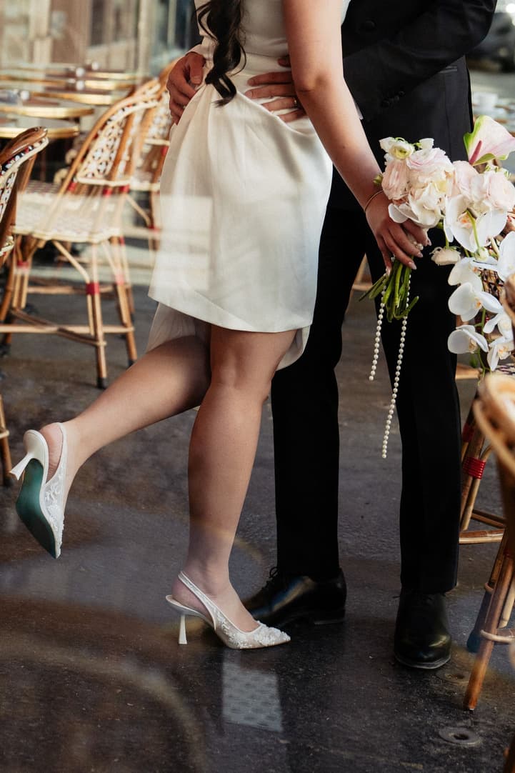 Nancy lifting her heel as she kisses Jason at the café
