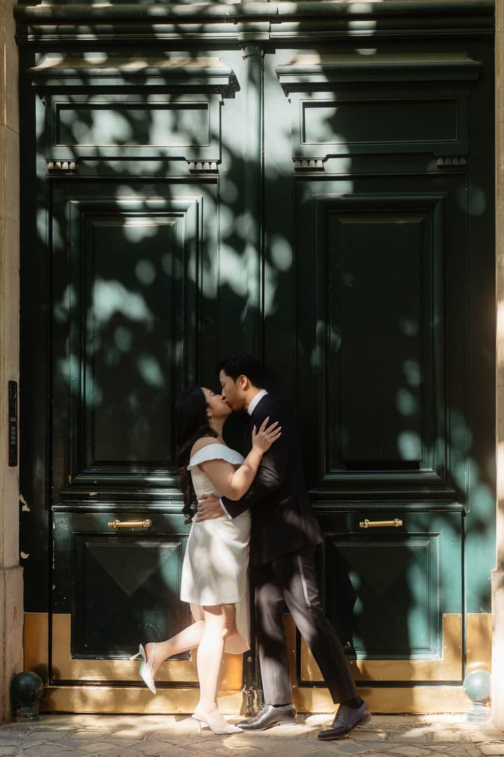 Nancy and Jason kissing against a tall green Parisian door