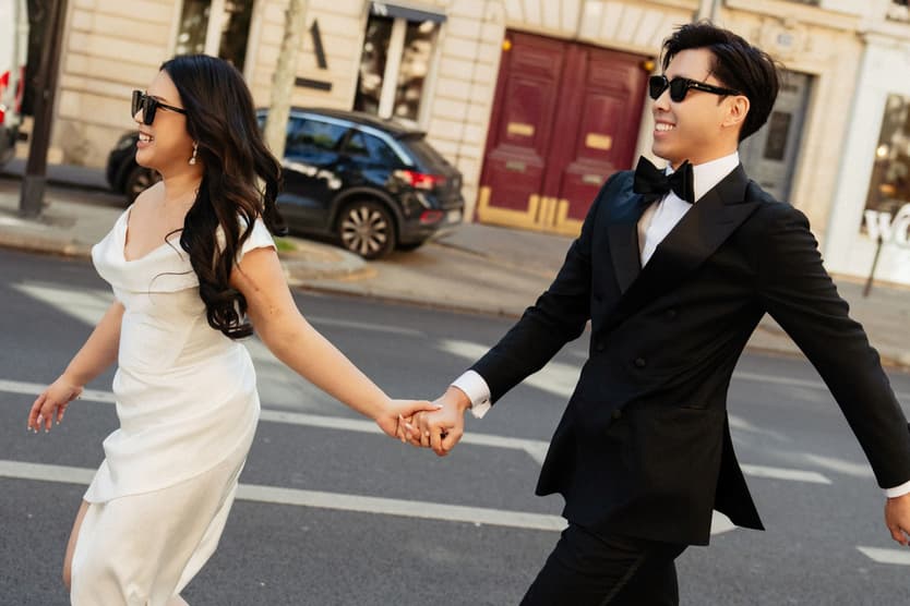Nancy and Jason striding hand in hand across a Paris street in the morning sun