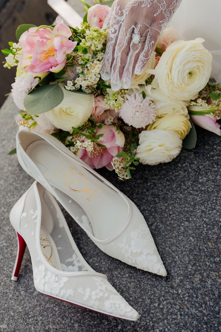 Lace bridal heels beside the bouquet on the stones of the Louvre