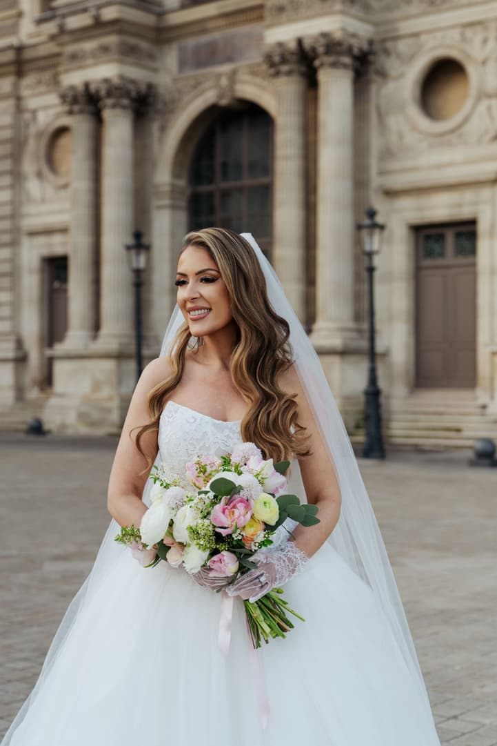 Bridal portrait of Aphrodite with her bouquet in the Louvre courtyard