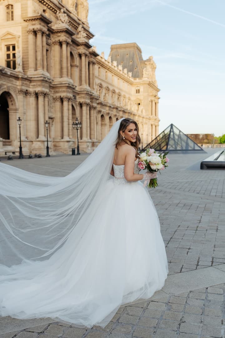 Aphrodite's cathedral veil flowing in the Louvre courtyard